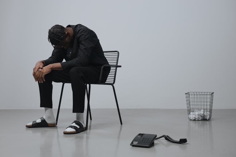 Man Sitting on a Black Metal Chair